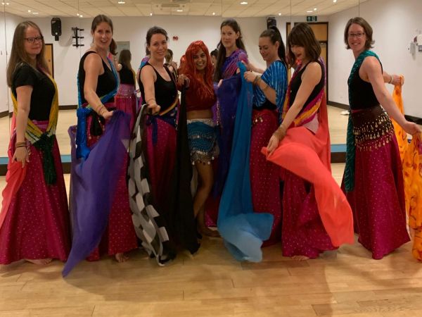 Belly dance class - dancers practicing hip movements and shimmies in studio