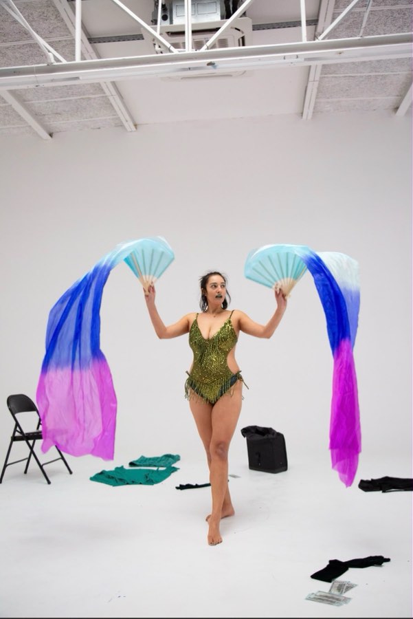 Burlesque dancer performing with flowing silk fans